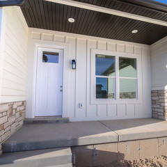 Square frame Entrance door to a white timber clad home