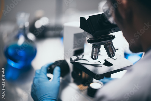 Fotomural Young scientist looking through a microscope in a laboratory