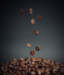 Coffee beans falling into a pile of coffee on the table