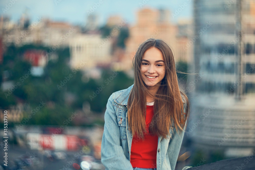 Lovely teen girl on cityscape background - obrazy, fototapety, plakaty 