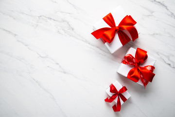 Wall Mural - white gifts with red ribbon, present on white marble background top view. happy holidays. valentine'