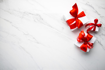 Wall Mural - white gifts with red ribbon, present on white marble background top view. happy holidays. valentine'