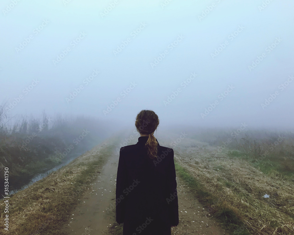 Una donna pensierosa nella nebbia nella ricerca di felicità  - obrazy, fototapety, plakaty 
