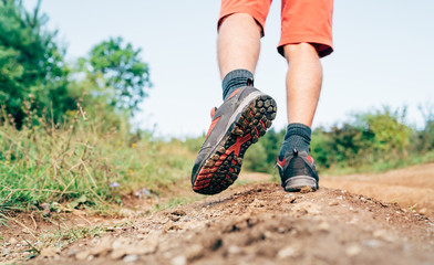 Wall Mural - trekking boot sole close up image traveler feet in trekking boots on mountain dirty path at summerti