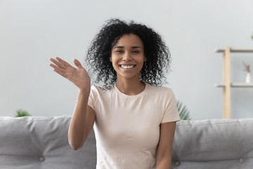 African woman feels happy wave hand looking at camera