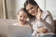 © fizkes - Happy mother and little daughter using laptop, making video call