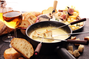 Wall Mural - Gourmet Swiss fondue dinner on a winter evening with assorted cheeses on a board alongside a heated pot of cheese fondue with two forks dipping