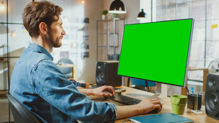 Aufkleber - Male Creative Designer with Beard and Jeans Shirt Works on His Personal Computer with Big Green Screen Mock Up Display. He Works in Cool Office Loft.
