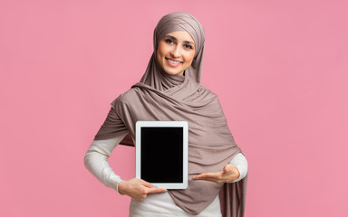 Wall Mural - Muslim girl in hijab pointing at digital tablet with black screen