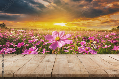 Fotografía Wooden table and cosmos flower field meadow with display montage for product