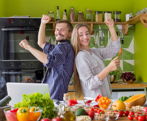 Happy millennial pair dancing and singing near table with food