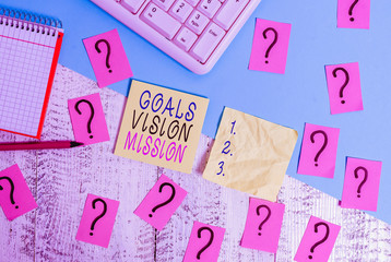 Text sign showing Goals Vision Mission. Business photo text practical planning process used to help community group Writing tools, computer stuff and math book sheet on top of wooden table