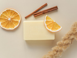 Handmade soap, dried plants, orange slices and cinnamon on beige background