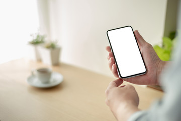 Mockup image blank white screen cell phone.man hand holding texting using mobile on desk at coffee shop.background empty space for advertise text.people contact marketing business,technology 