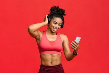 Wall Mural - Happy black fitness girl choosing music on smartphone for exercising