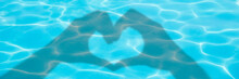 Shadows Of Hands Forming A Heart On Blue Swimming Pool Water Background, Panoramic Valentines Day Or Summer Banner