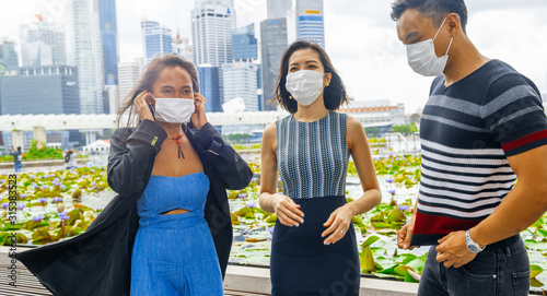 Three asian friends wearing masks strolling around the city. Pollution and environment concept