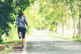 Sporty asian woman runner running and jogging through the road.  Outdoor Workout in a Park. Weight Loss and Healthy Concept