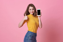 Portrait Of Happy Young Woman Showing At Blank Screen Mobile Phone Isolated Over Pink Background.