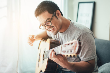 artist playing acoustic guitar,sing folk song.happy man sitting enjoy on sofa in relax time.concept for art and music therapy for relaxation and healing for people