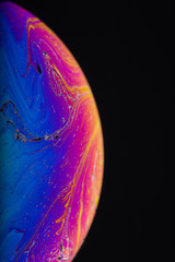Wall Mural - close up macro photograph of the psychedelic rainbow of colors mixing and swirling in a soap bubble 