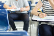 © panitan - high school,university student study.hands holding pencil writing paper answer sheet.sitting lecture chair taking final exam attending in examination classroom.concept scholarship for education abroad