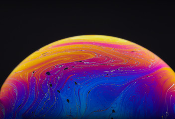 Wall Mural - close up macro photograph of the psychedelic rainbow of colors mixing and swirling in a soap bubble 