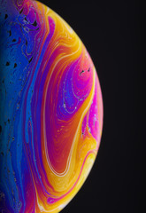 Wall Mural - close up macro photograph of the psychedelic rainbow of colors mixing and swirling in a soap bubble 