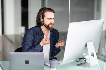 Angry call center operator working at his desk on computer and laptop