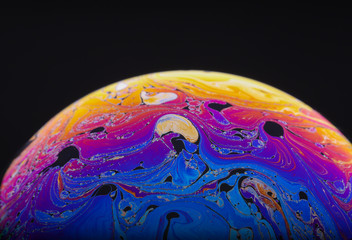 Wall Mural - close up macro photograph of the psychedelic rainbow of colors mixing and swirling in a soap bubble 