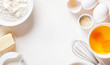 © Светлана Монякова - Frame of food ingredients for baking on a white background, top view, copy space. Flour, eggs, sugar and milk in white bowls and a whisk. Cooking and baking concept, flat lay.
