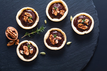 Wall Mural - Food concept Homemade rustic organic mini chocolate and walnuts tarts on black slate stone plate with copy space