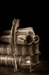 Wall Mural - Quill pen and rolled up papyrus sheets with old books, sepia effect