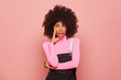 © Indico Studio/ADDICTIVE STOCK - Amazed African American female wearing pink turtleneck and black overall touching face and looking at camera with open mouth surprised with news