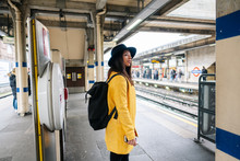 Side View Of Happy Stylish Female Smiling Waiting For A Train While Standing On Platform On Station In London, United Kingdom