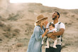 © Gabriel Trujillo/ADDICTIVE STOCK - Happy black bearded man carrying little baby and holding hand of blond wife wearing denim shirt jeans and hat while standing on sandy land