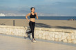 © Juan Alberto Ruiz/ADDICTIVE STOCK - Motivated young female athlete in active black wear and sneakers jogging along rocky fence by the beach on empty seashore