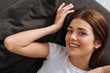 © LIGHTFIELD STUDIOS - top view of happy woman looking at camera while resting on sofa in living room