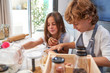 © PHILIPPE DEGROOTE/ADDICTIVE STOCK - Little male and female kids in back splashes making paste while using different cooking implements at modern kitchen