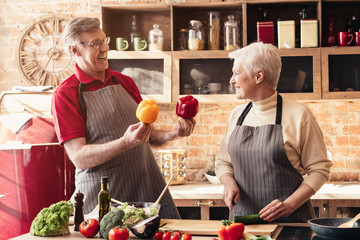 Senior spouses cooking healthy salad at kitchen