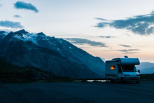 White Camper Moving On Road Along Lake With Crystal Water In Twilight In Switzerland 
