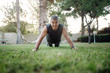 © Santi Miquel/ADDICTIVE STOCK - From below strong active mature man looking at camera in good sportive shape planking and pushing up in green meadow in park in summer day