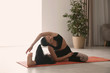 © New Africa - Woman practicing revolved head to knee asana in yoga studio. Parivrtta janu sirsasana pose