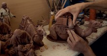 Crop Person Smoothing Statuette Of Decorative Clay Camel On Table In Pottery