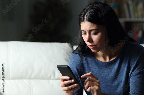 Fotomural Worried woman checking cell phone text in the night