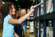 © DragonImages - Horizontal side view waist up shot of teenage girl taking book from shelf in modern bookstore