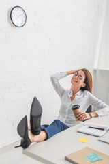 Wall Mural - selective focus of happy businesswoman holding paper cup while chilling in office