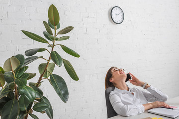 Wall Mural - happy businesswoman relaxing and talking on smartphone in office