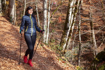 Active way of life, The girl is walking along the path in the woods by Scandinavian walking. Walk in the autumn forest