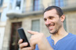 © Antonioguillem - Happy adult man browsing phone content in the street